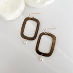 Textured bronze rectangular hoop earrings with freshwater pearl drops by Dawn Carlson Designs on white fabric with cream flowers