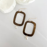 Textured bronze rectangular hoop earrings with freshwater pearl drops by Dawn Carlson Designs on white fabric with cream flowers