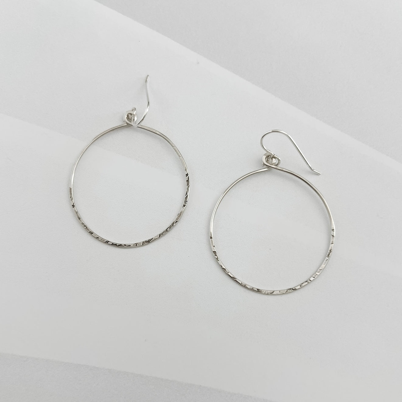 Pair of handcrafted hammered sterling silver circle hoop earrings with textured finish and French ear wires, lightweight everyday hoops by Dawn Carlson Designs