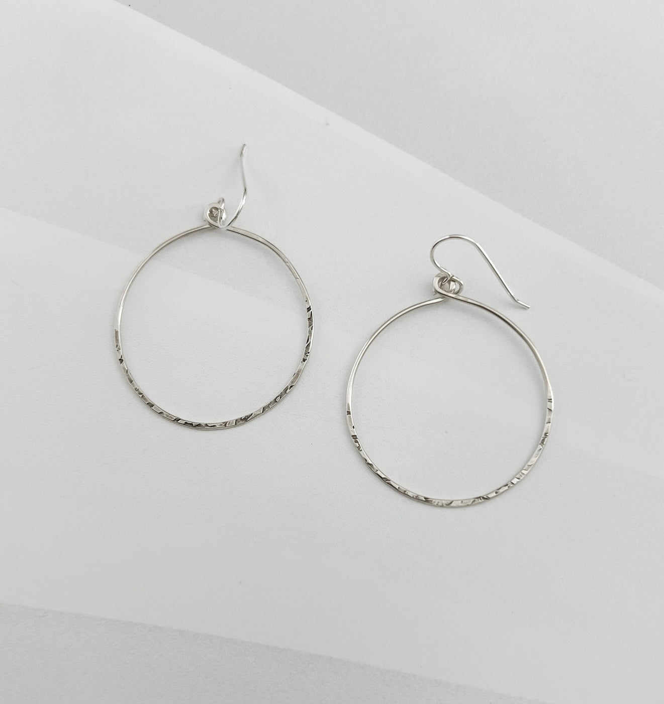 Pair of handcrafted hammered sterling silver circle hoop earrings with textured finish and French ear wires, lightweight everyday hoops by Dawn Carlson Designs