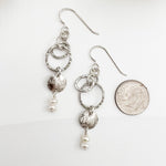 Sterling silver and pearl dangle earrings shown next to dime for scale, featuring textured hoops and luminous freshwater pearl drops, handmade by Dawn Carlson Designs