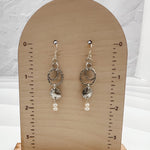 Caroline silver and pearl earrings displayed on wooden earring card showing 2-inch length, featuring hammered sterling silver circles and freshwater pearl accents