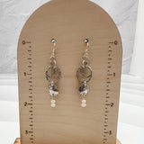Caroline silver and pearl earrings displayed on wooden earring card showing 2-inch length, featuring hammered sterling silver circles and freshwater pearl accents