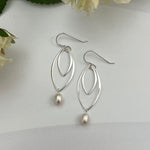 Double marquis sterling silver earrings with freshwater pearls by Dawn Carlson Designs, styled with white flowers on textured background