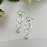 Double marquis sterling silver earrings with freshwater pearls by Dawn Carlson Designs, styled with white flowers on textured background