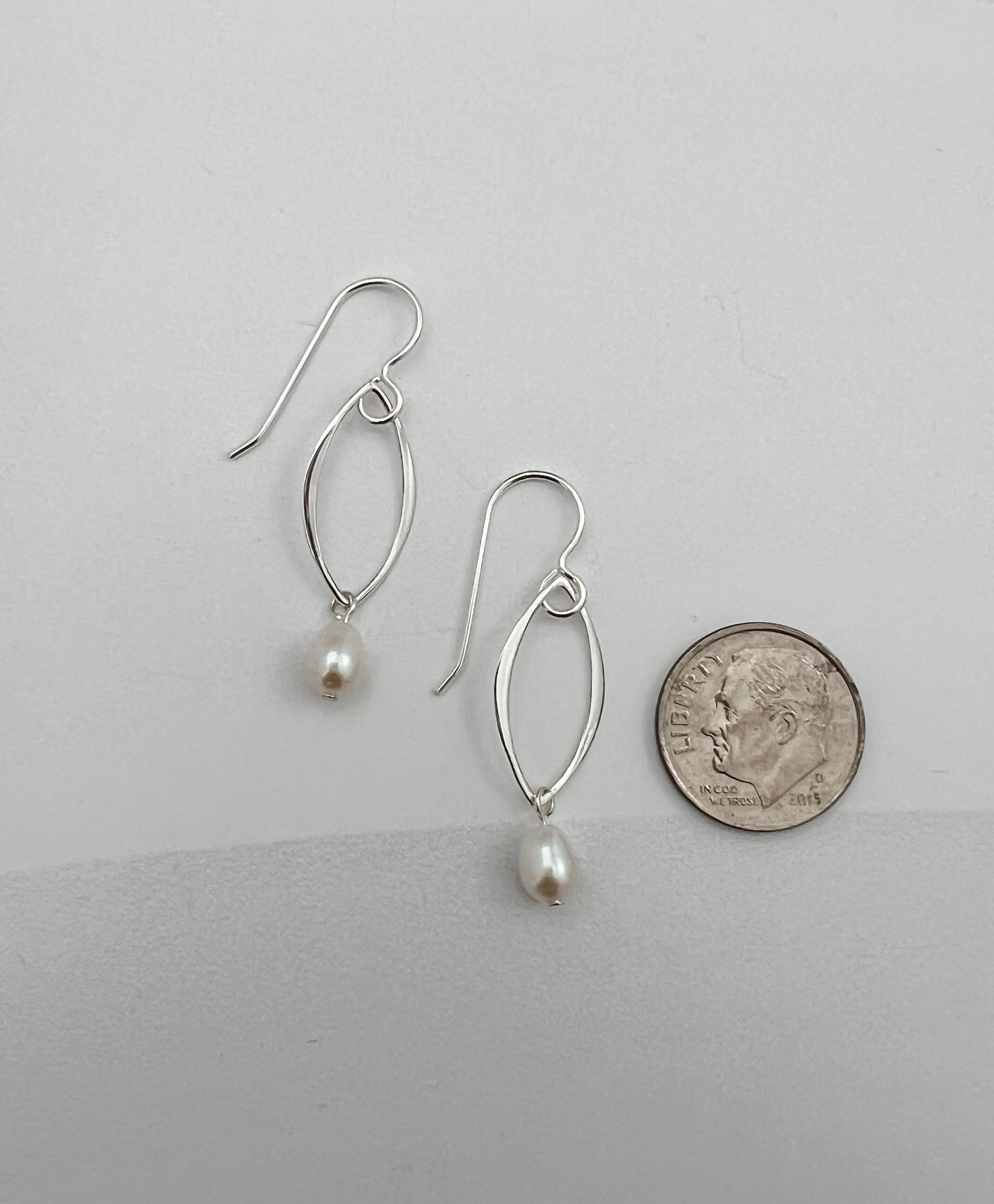 Sterling silver marquis pearl earrings next to dime showing 1.5 inch length and delicate size