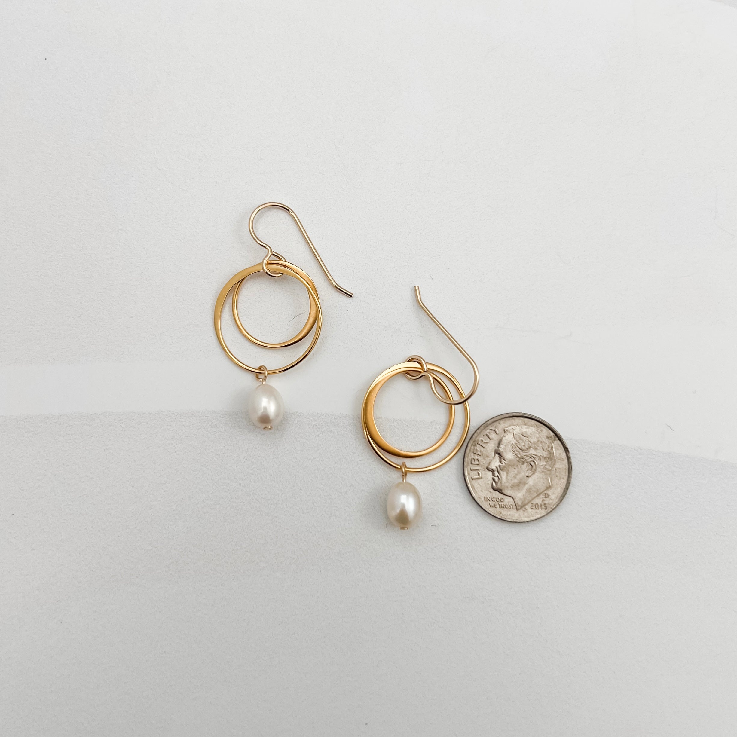 Small double hoop pearl earrings shown with dime for scale