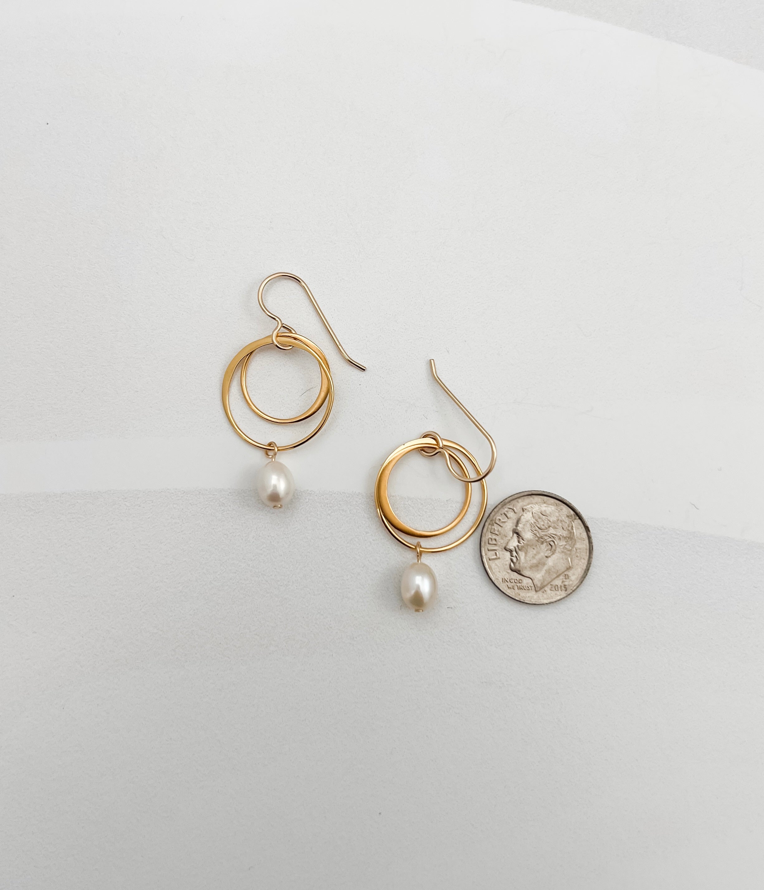 Small double hoop pearl earrings shown with dime for scale