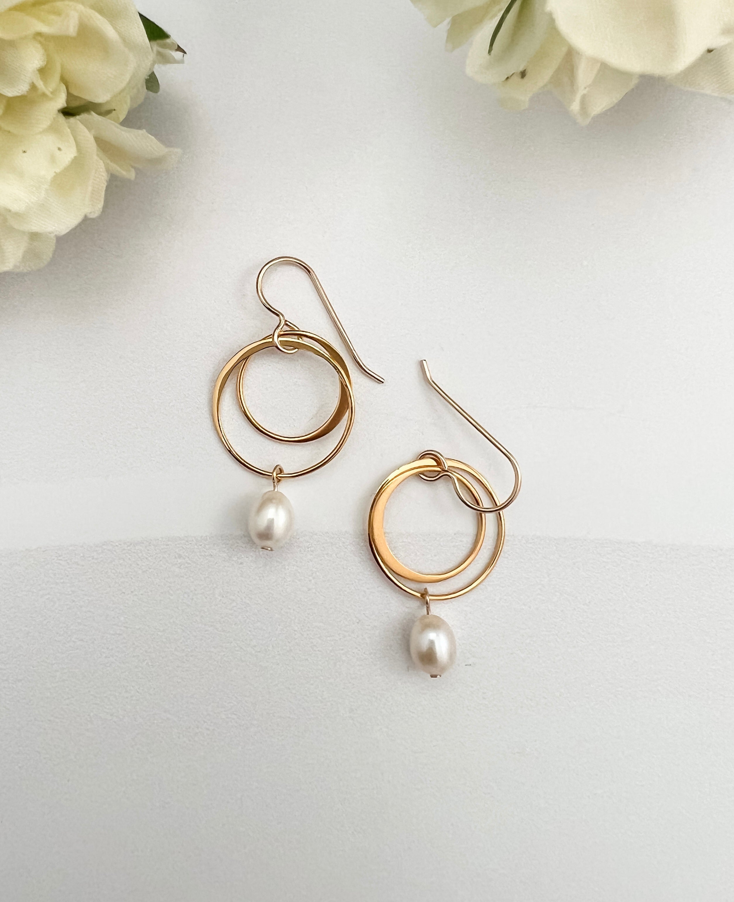 Gold vermeil double hoop earrings with freshwater pearl drops on white background with two flowers