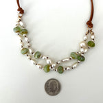 Double-strand freshwater pearl necklace on natural leather cord, accented with faceted green Czech glass beads and 14k gold filled jump rings, shown next to a dime for scale
