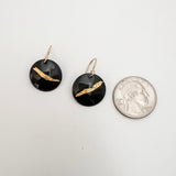 Black enamel and 24k gold foil disc earrings shown next to a quarter for scale, handcrafted by Dawn Carlson Designs