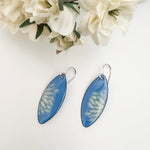 French blue enamel marquise earrings with cream flower petal pattern on sterling silver ear wires, styled with white fabric flowers