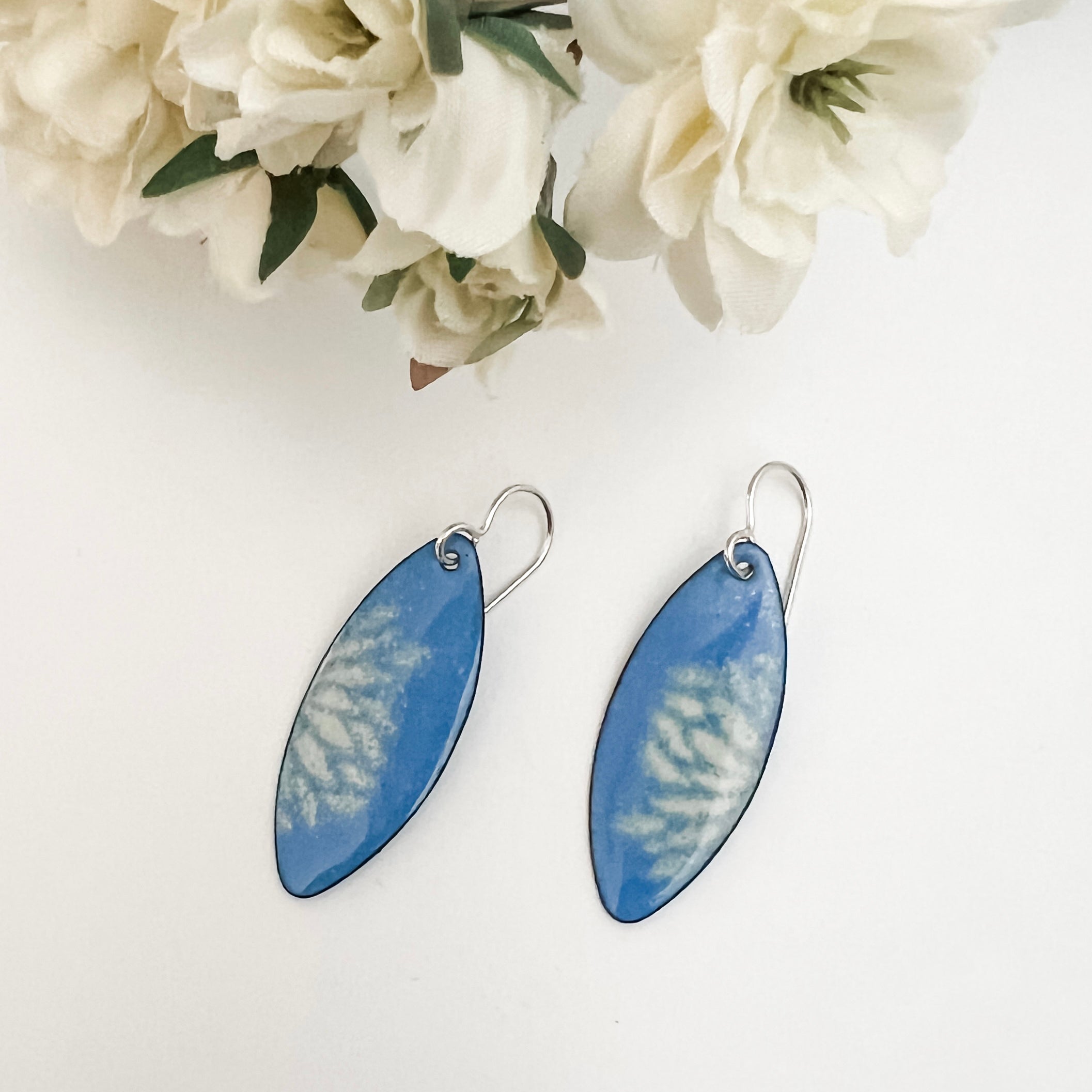 French blue enamel marquise earrings with cream flower petal pattern on sterling silver ear wires, styled with white fabric flowers