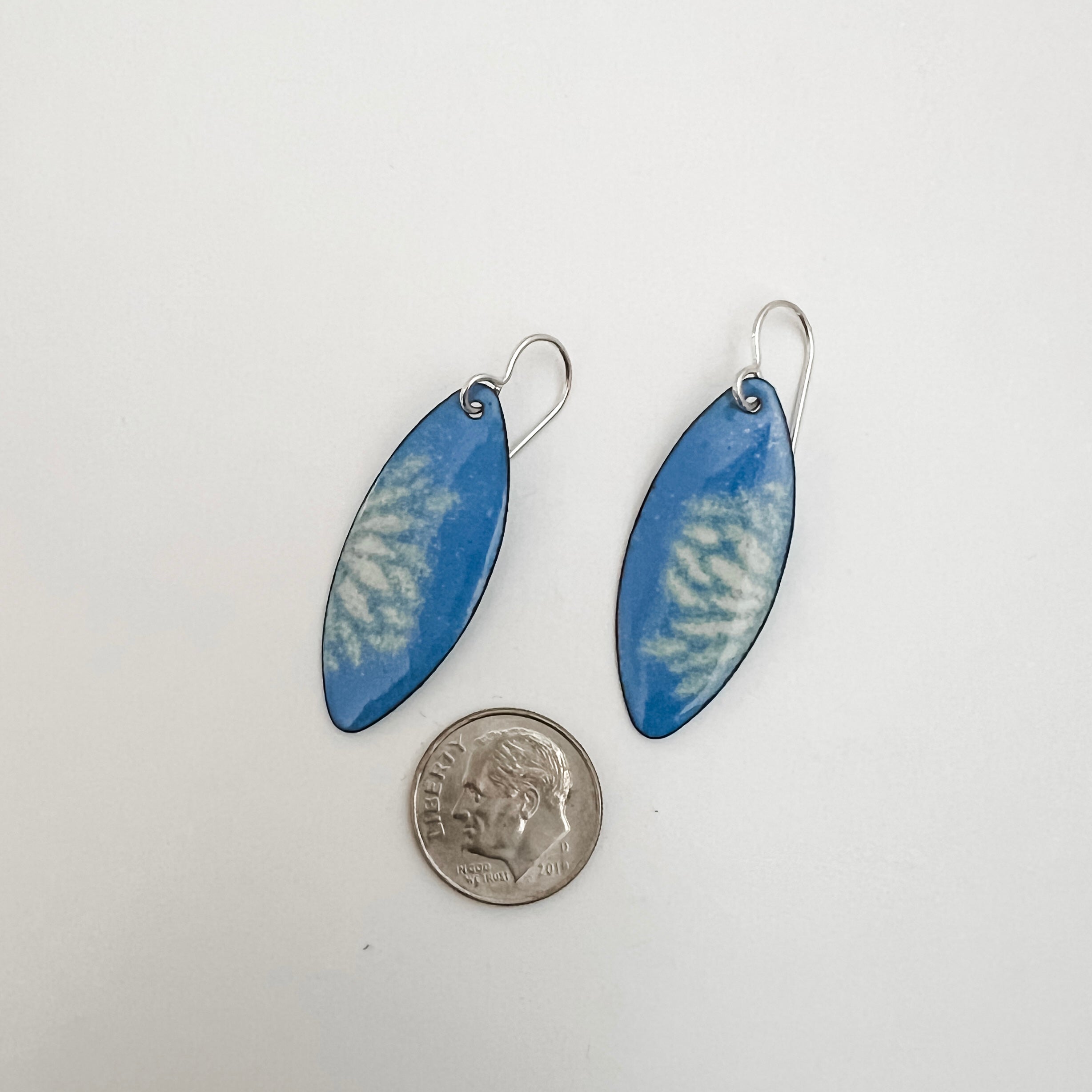 Handmade French blue vitreous enamel earrings shown next to a quarter for scale, marquise shape with sifted cream petal design