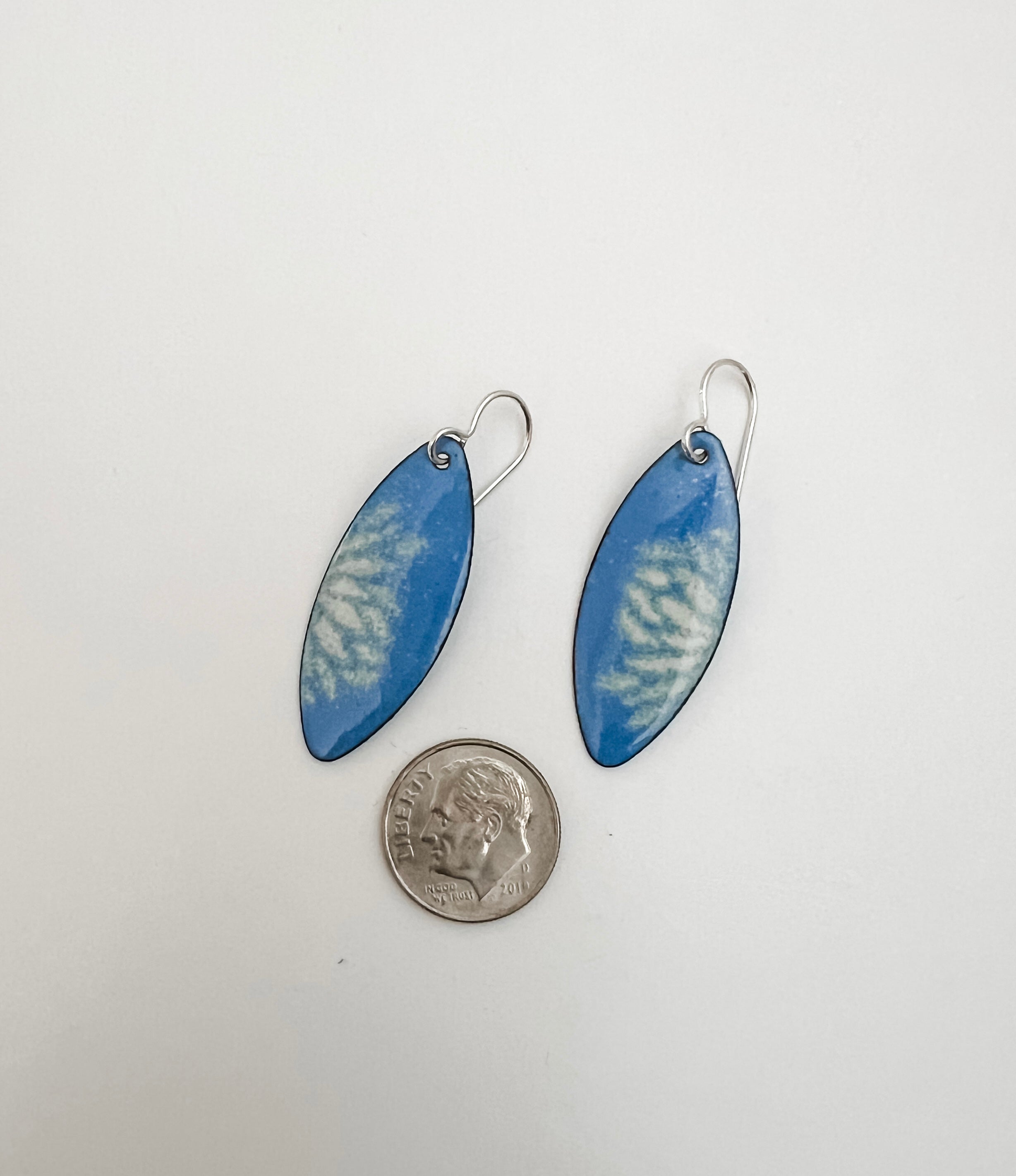 Handmade French blue vitreous enamel earrings shown next to a quarter for scale, marquise shape with sifted cream petal design