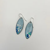 Handcrafted light blue enamel earrings with dark blue, cream, and seafoam splashes on sterling silver ear wires by Dawn Carlson Designs on a white background.