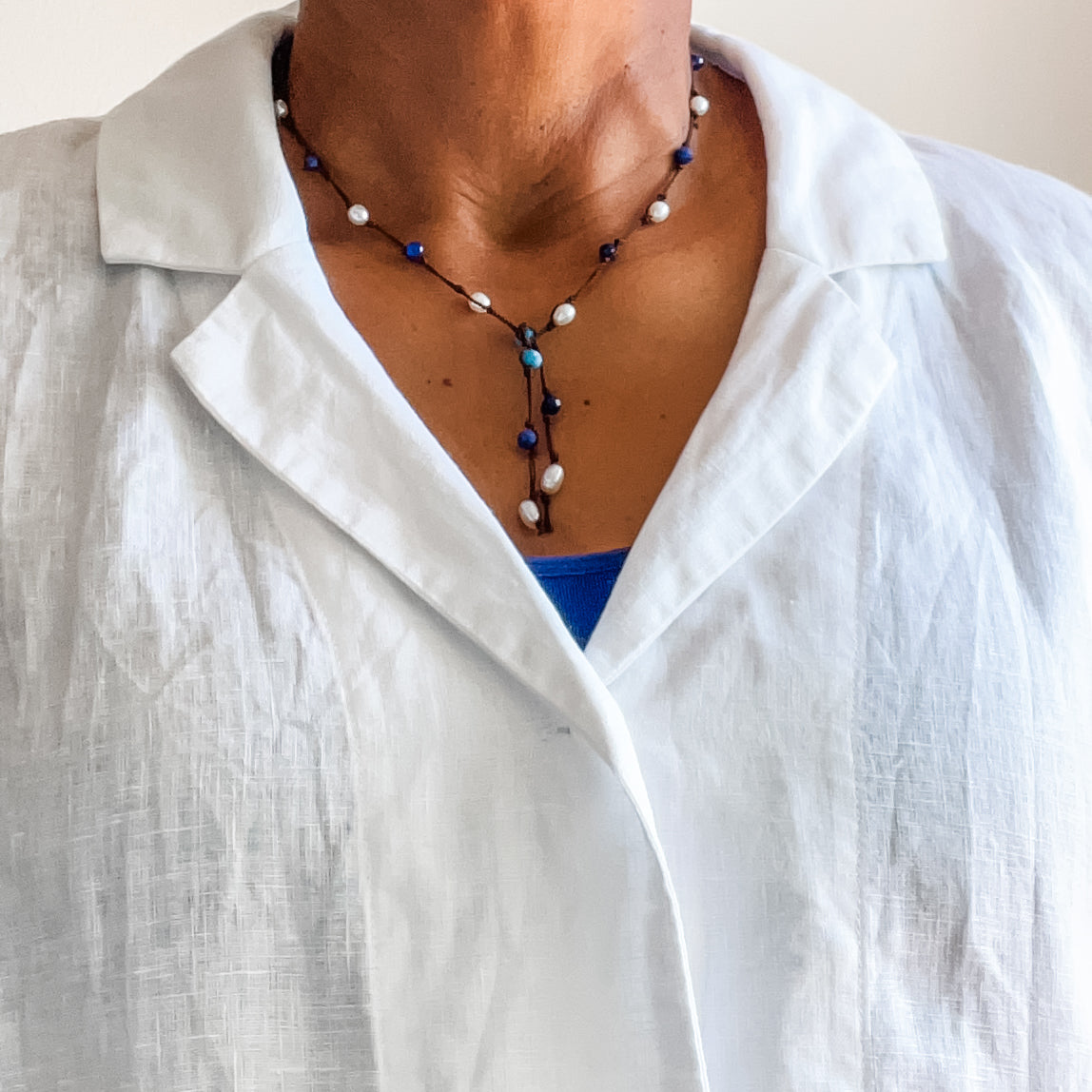 Apatite, sodalite and pearl lariat shown on model wearing a white linen blouse. Dawn Carlson Designs
