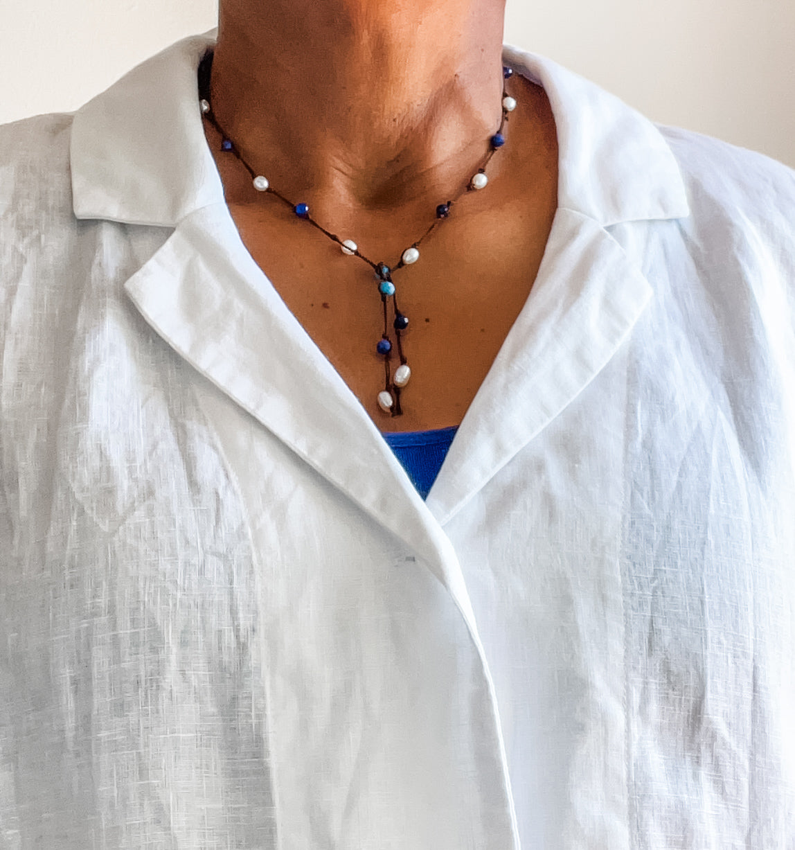 Apatite, sodalite and pearl lariat shown on model wearing a white linen blouse. Dawn Carlson Designs