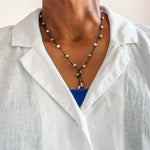 Pearl and peridot hand knotted lariat necklace shown on a person wearing a white linen blouse. Clasp free design.