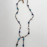 Apatite, sodalite and pearls knotted on brown cord with white background and branded tag.