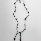 Apatite, sodalite and pearls knotted on brown cord with white background and branded tag.