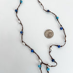 close up of hand knotted pearls, apatite and sodalite beads necklace. Lariat style, no clasp. Shown with a dime for reference on a white background.
