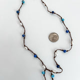 close up of hand knotted pearls, apatite and sodalite beads necklace. Lariat style, no clasp. Shown with a dime for reference on a white background.