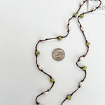 Close up of hand knotted freshwater pearls and peridot on nylon cord, artisan jewelry detail. Showing a dime next to the necklace for reference.