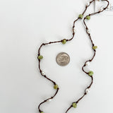 Close up of hand knotted freshwater pearls and peridot on nylon cord, artisan jewelry detail. Showing a dime next to the necklace for reference.
