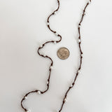 Freshwater pearls necklace hand knotted on brown cord shown with a dime for reference. Lariat style necklace
