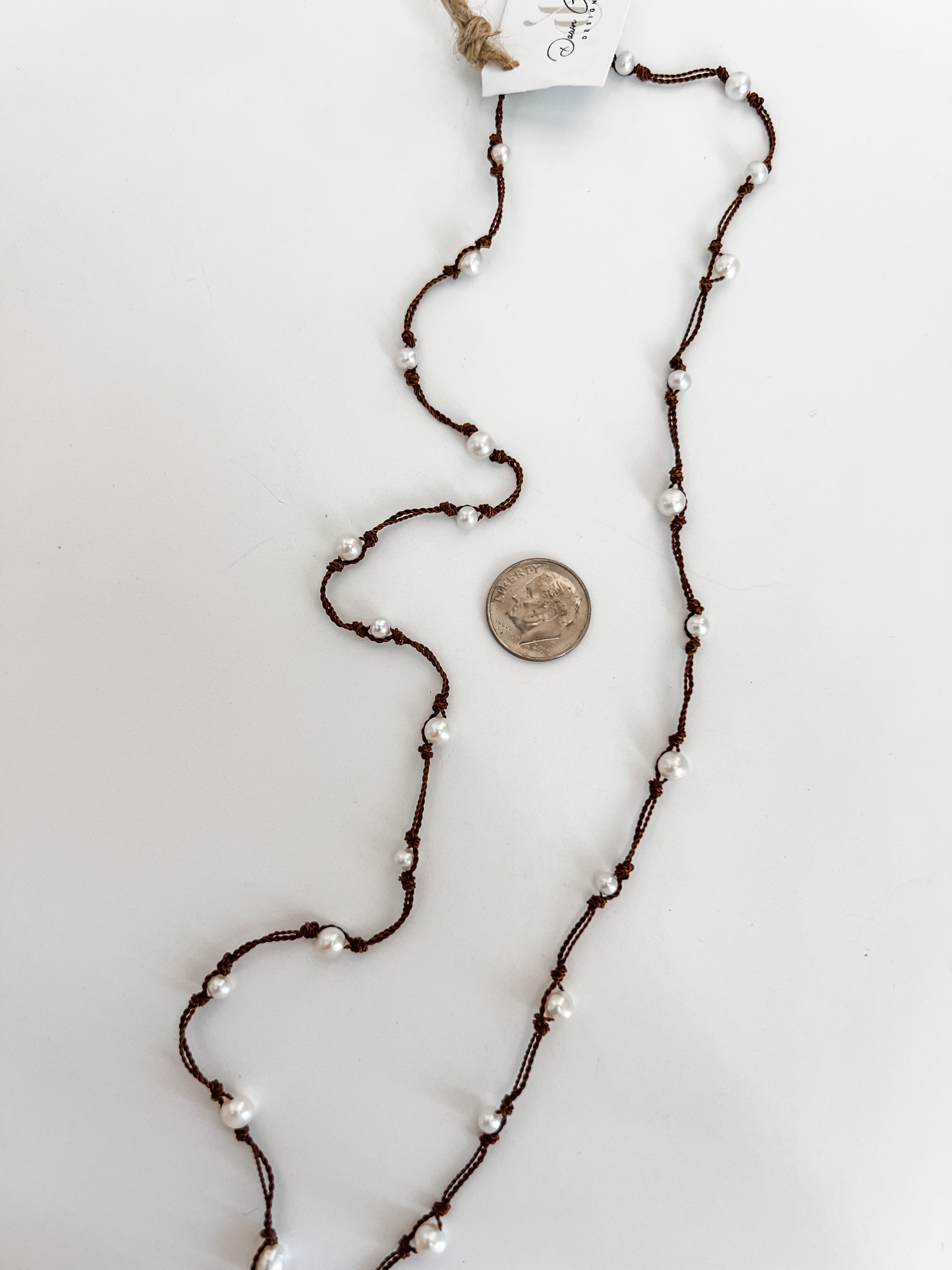 Freshwater pearls necklace hand knotted on brown cord shown with a dime for reference. Lariat style necklace