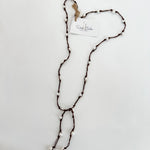 Freshwater pearls hand knotted on brown cord for a lariat necklace. Shown on a white background with a branded tag.